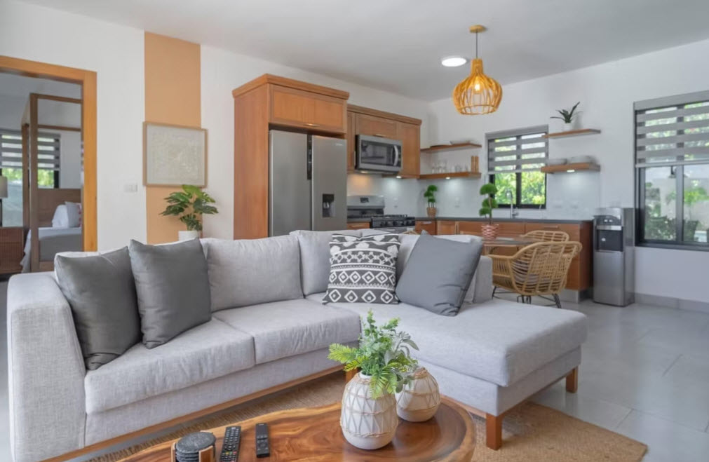 Modern living room with sectional sofa, wood accents, and open kitchen