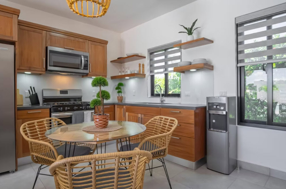 Modern kitchen with wooden cabinets, stainless steel appliances, and a round dining table.