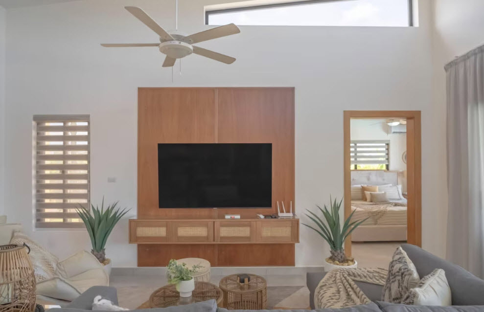 Modern living room with large TV, wood accent wall, and view into bedroom.