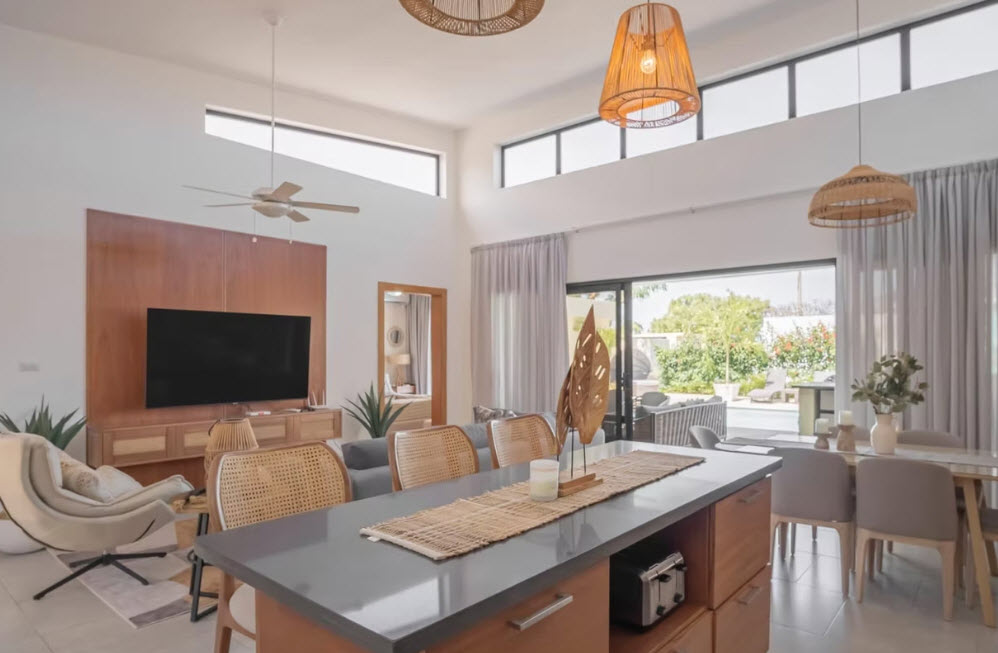 Modern living room with vaulted ceilings, large windows, and outdoor pool view.