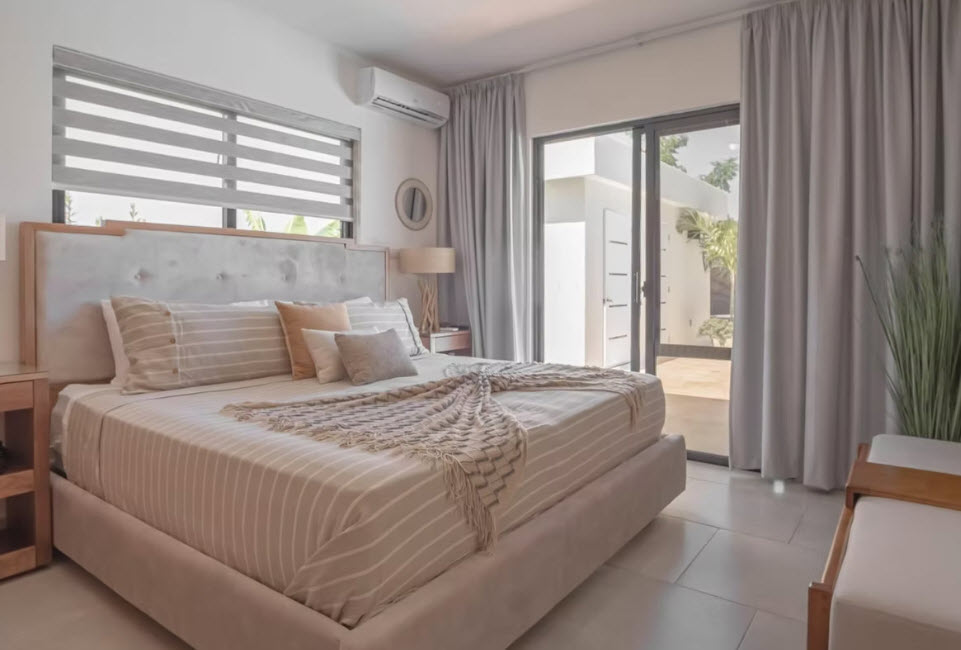 Modern bedroom with a large bed, neutral tones, and balcony access