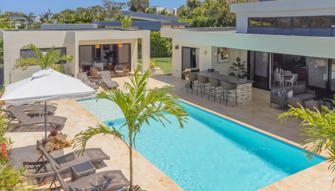 Modern villa with swimming pool, lounge chairs, and outdoor bar