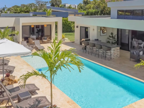 Modern villa with swimming pool, lounge chairs, and outdoor bar