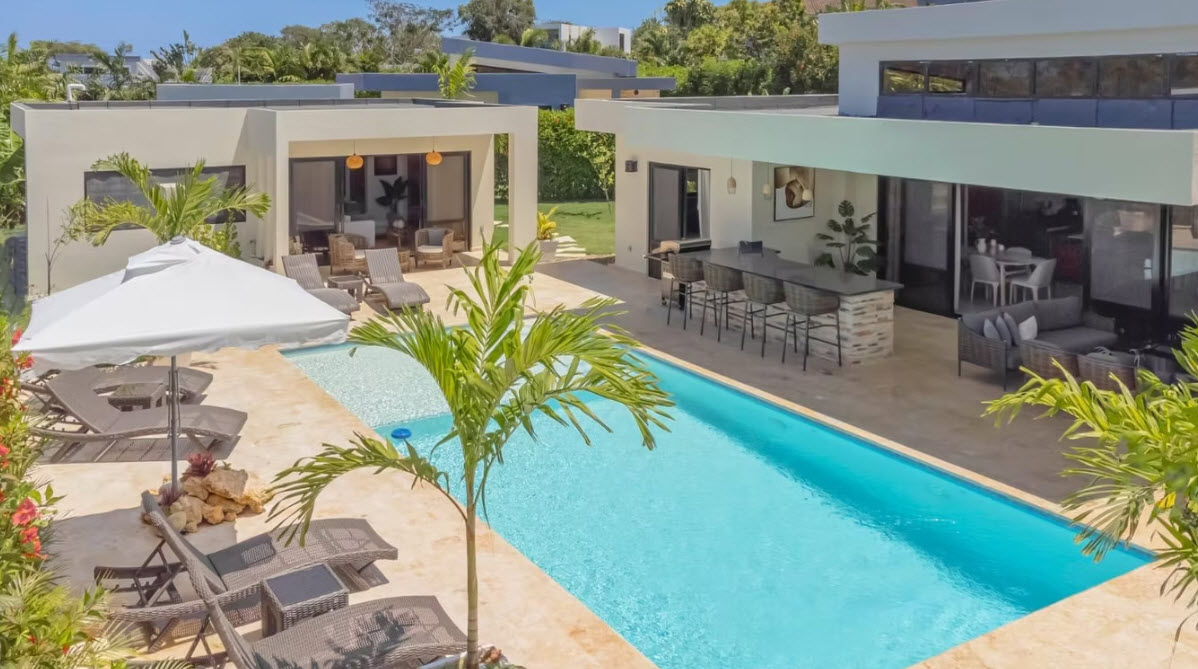 Modern villa with swimming pool, lounge chairs, and outdoor bar