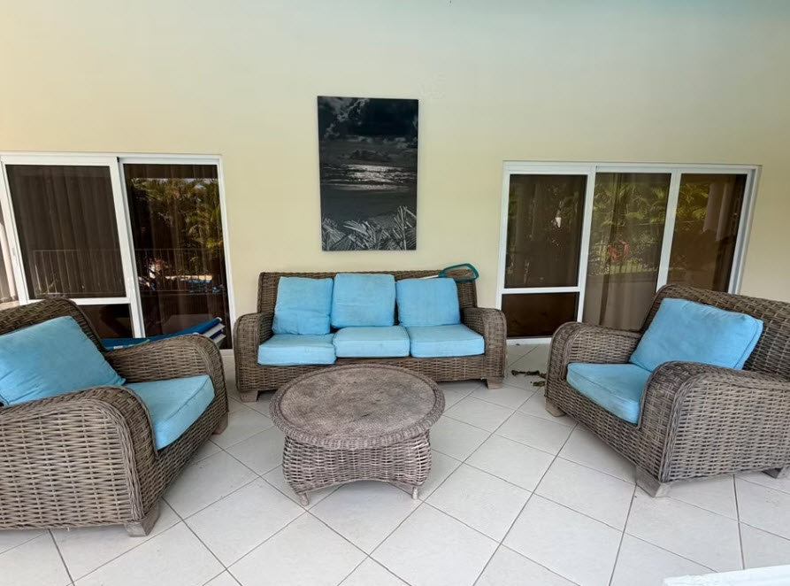 Wicker patio furniture with blue cushions on a tiled porch.