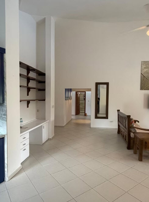 Spacious living room with vaulted ceilings, built-in desk, and wooden furniture