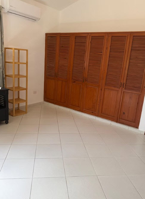 Wooden louvered closet doors and a light wood shelf unit in a tiled room