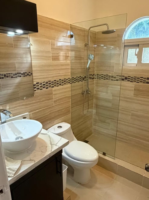 Modern bathroom with a vessel sink, toilet, and glass-enclosed shower
