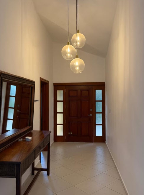 Entryway with wooden doors, console table, mirror, and pendant lights