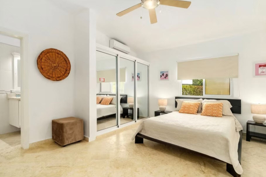 Bright, modern bedroom with large mirrored closet doors and tropical garden view