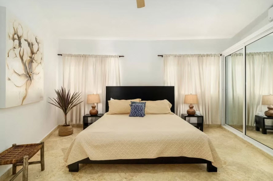 Modern bedroom with queen bed, beige quilt, and mirrored closet