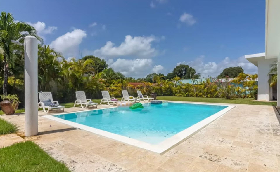 Luxury villa with swimming pool, lounge chairs, and inflatable toys.