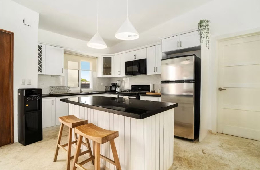 Modern white kitchen with black granite island and stainless steel appliances