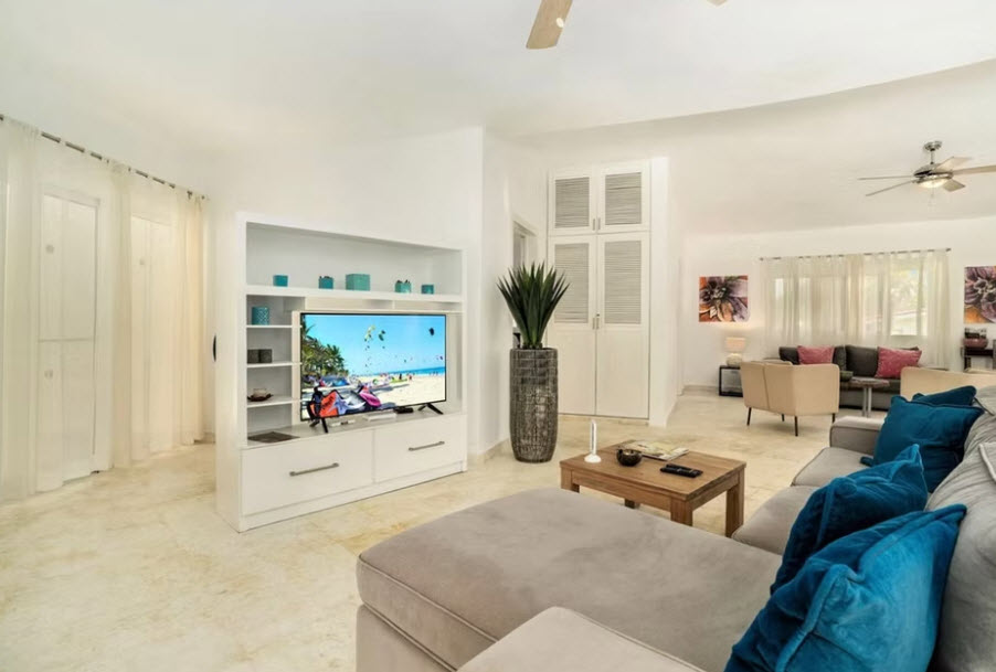 Modern living room with large TV displaying a beach scene, plush sofa, and coffee table.