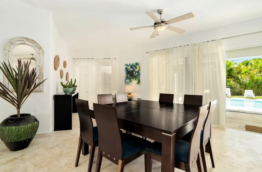 Elegant dining room with dark wood table, chairs, and view of pool