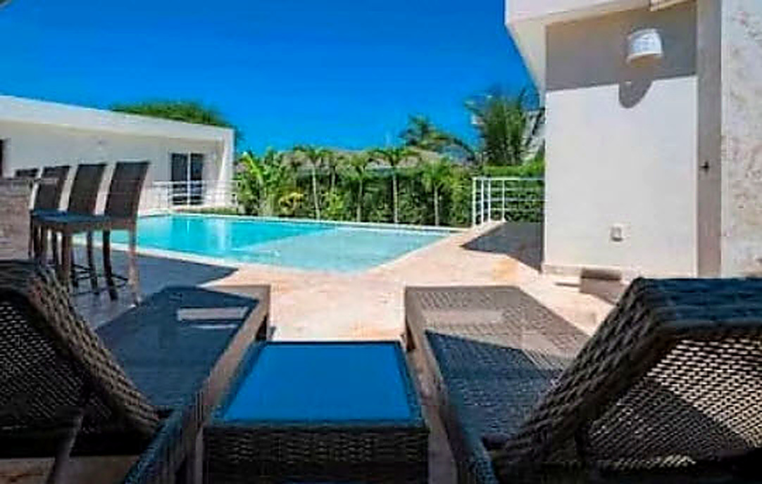 Luxury villa with pool and lounge chairs in tropical setting