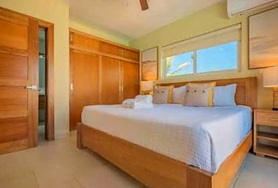 Spacious bedroom with a king-size bed, wooden wardrobe, and large window.