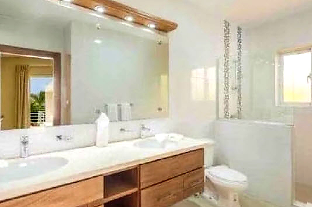 Modern bathroom with double vanity, large mirror, and toilet