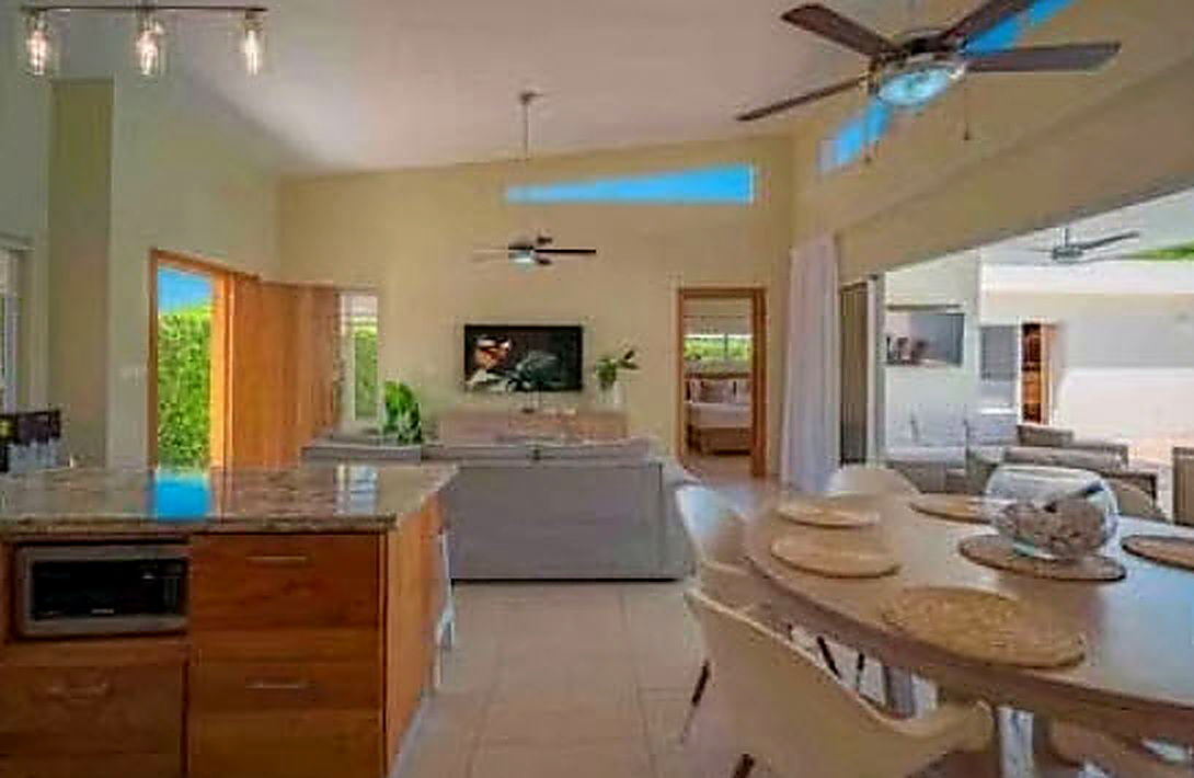 Open-plan living area with kitchen island, dining table, and living room with TV.