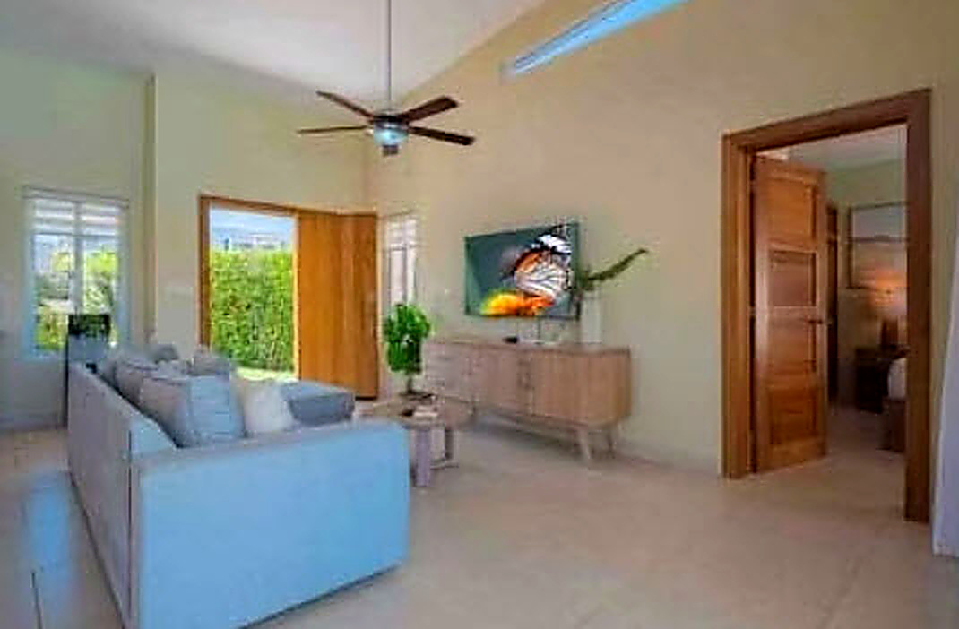 Modern living room with light blue sofa, ceiling fan, and large screen TV showing butterfly.