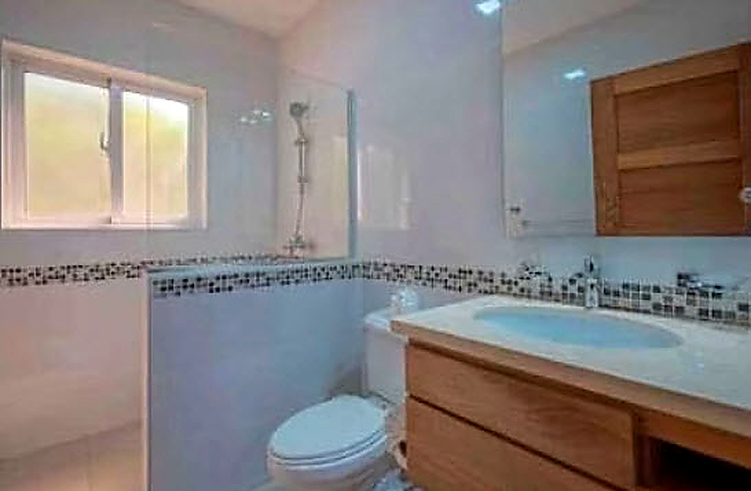 Modern bathroom with a wooden vanity, white toilet, and a walk-in shower.