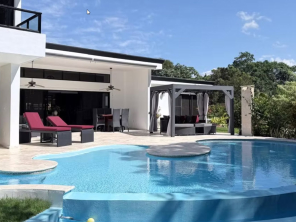Modern luxury villa with a large, inviting swimming pool and outdoor seating area.