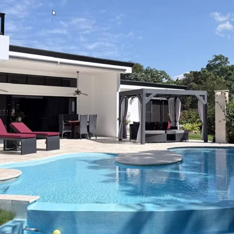 Modern luxury villa with a large, inviting swimming pool and outdoor seating area.