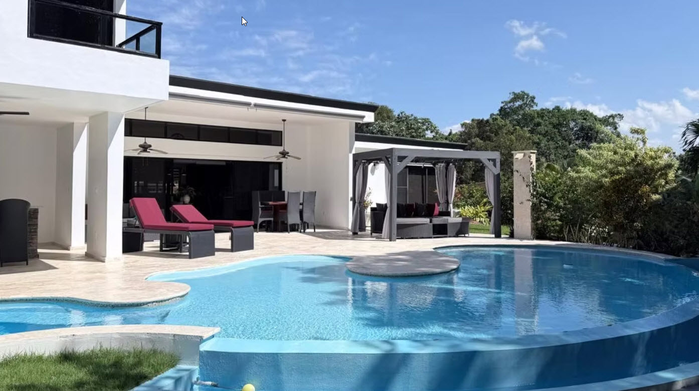 Modern luxury villa with a large, inviting swimming pool and outdoor seating area.