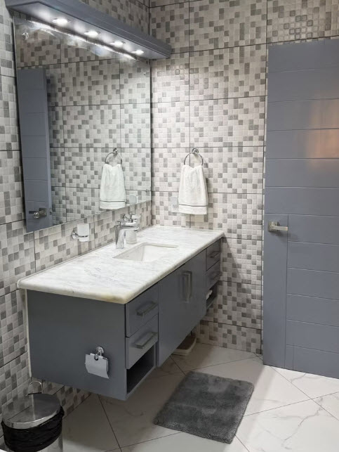 Modern grey bathroom with marble countertop vanity and tiled walls.