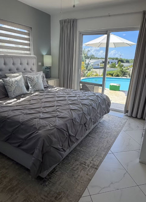 Luxurious bedroom with a view of a tropical pool and patio