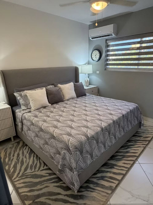 Modern gray bedroom with king-size bed, patterned bedding, and zebra rug