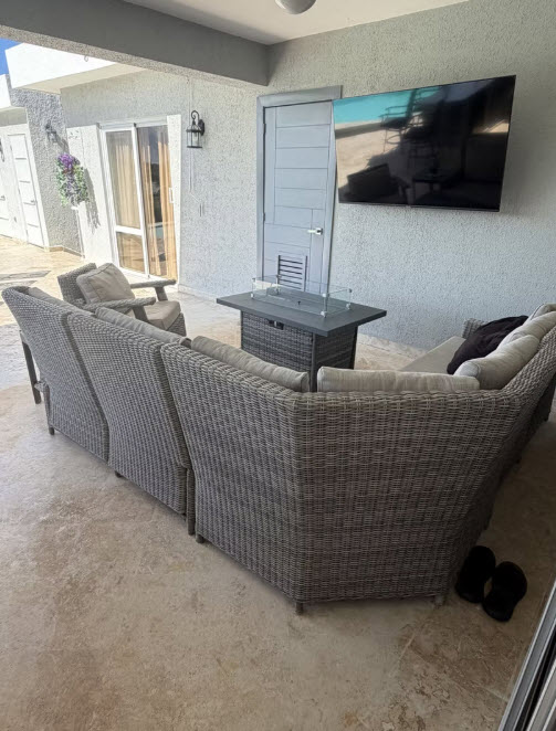 Outdoor patio with sectional sofa, fire pit table, and wall-mounted TV