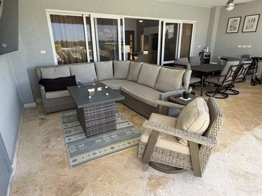 Wicker patio furniture with sectional sofa, fire pit table, and dining set on tiled balcony