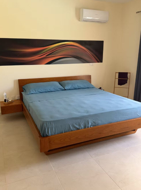 Modern bedroom with wooden bed, blue linens, and abstract art