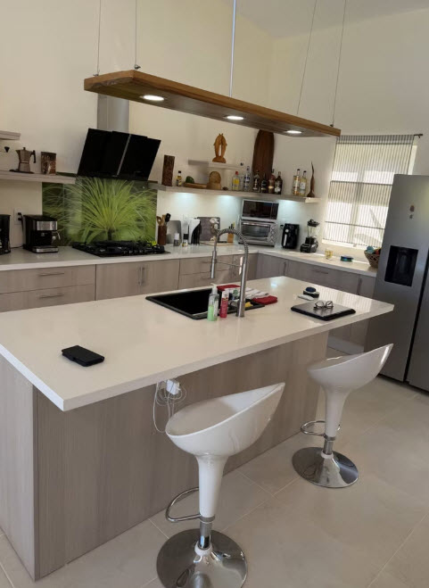 Modern kitchen with island, white stools, and stainless steel appliances