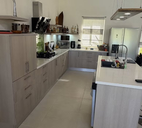 Modern, spacious kitchen with light wood cabinets, stainless steel appliances, and a large island.
