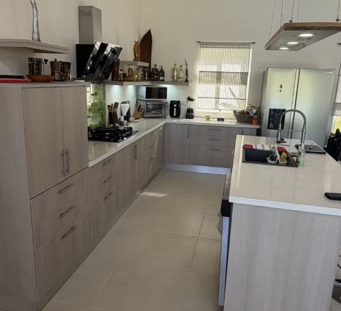 Modern, spacious kitchen with light wood cabinets, stainless steel appliances, and a large island.