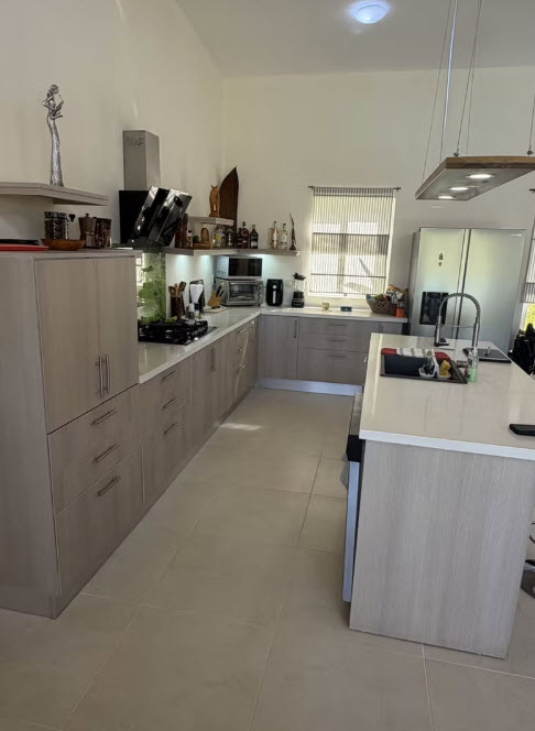 Modern, spacious kitchen with light wood cabinets, stainless steel appliances, and a large island.