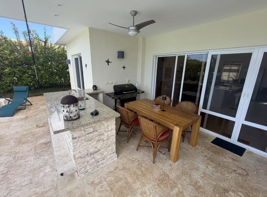Outdoor kitchen with granite island, grill, and dining table