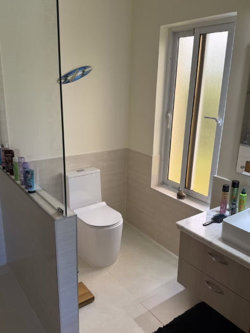 Modern bathroom with white toilet, vanity, and frosted window.