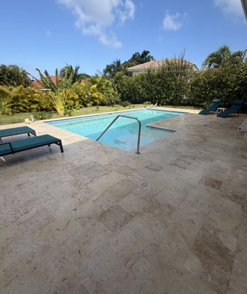 Luxury backyard swimming pool with lounge chairs and tropical landscaping