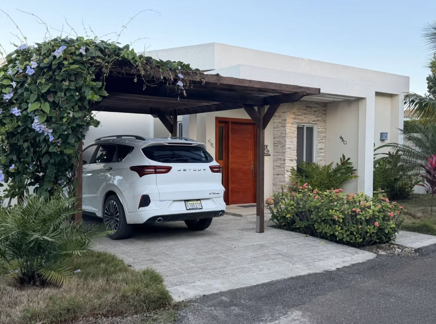 White SUV parked under a wooden pergola with climbing vines and blue flowers