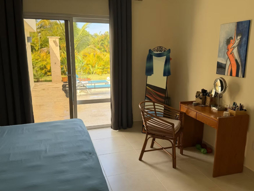 Bedroom with vanity, mirror, and patio view of pool and palm trees