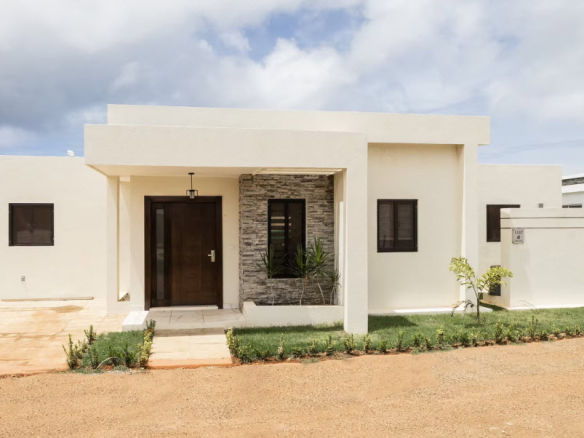 Modern beige house with a stone accent wall and dark wood door.