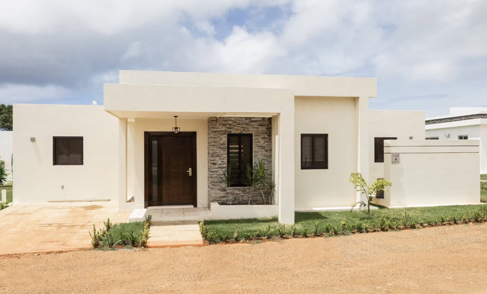 Modern beige house with a stone accent wall and dark wood door.