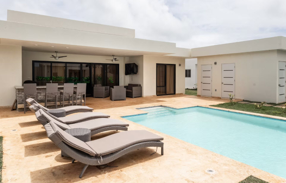 Modern villa with swimming pool, lounge chairs, and outdoor bar