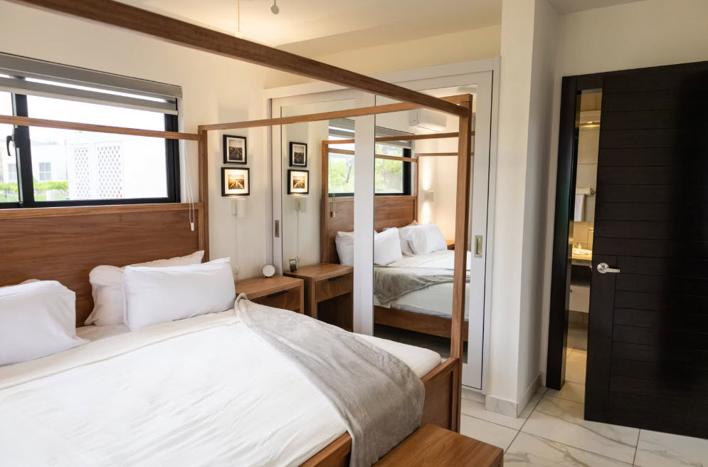 Luxurious wooden four-poster bed with white linens in a modern bedroom
