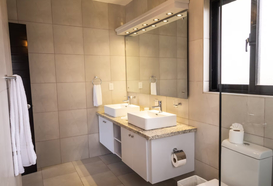Modern bathroom with double square sinks, granite countertop, and large mirror