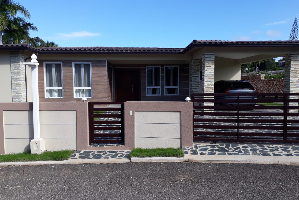 Modern house with a car in the driveway and a stone fence