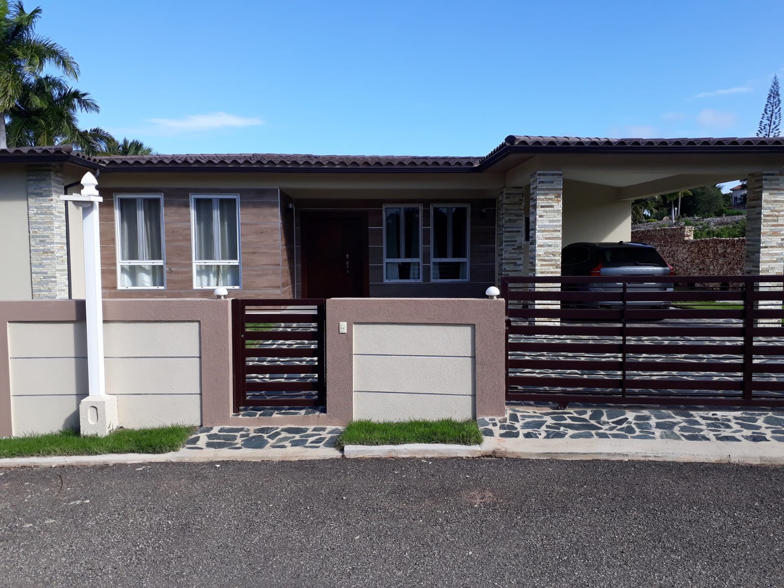 Modern house with a car in the driveway and a stone fence